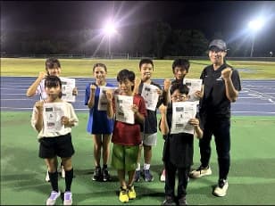 夜のグラウンドで記録証を持つ受講生とコーチの集合写真
