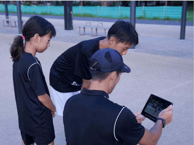 タブレットで走りの動画を確認するコーチと子ども